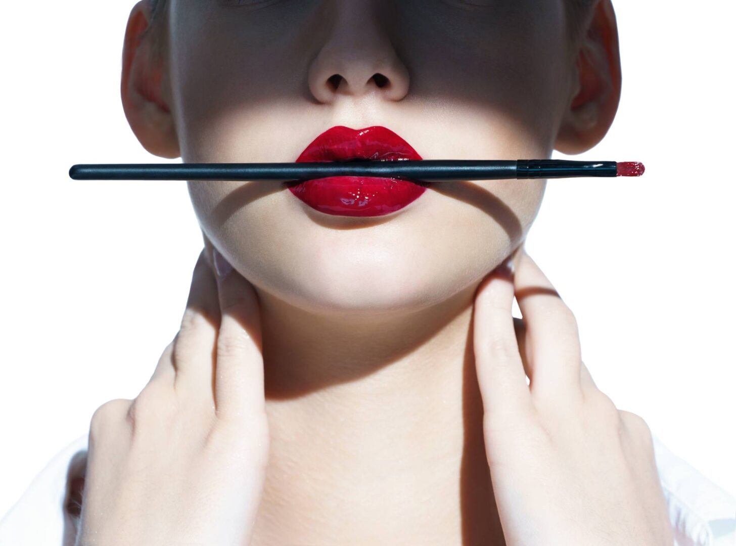 A woman with red lipstick holding onto a black pencil.