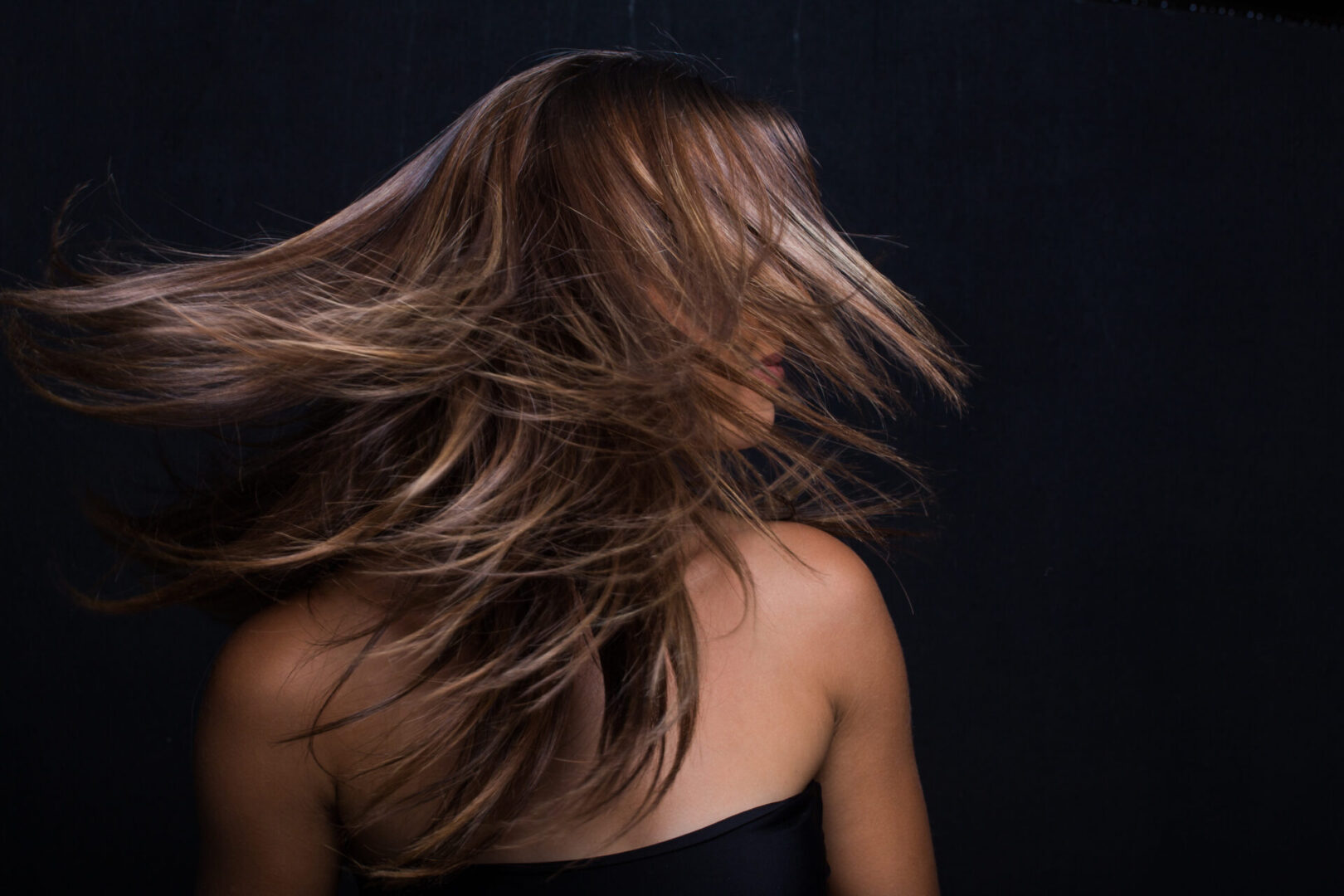 A woman with long hair is standing in the dark.