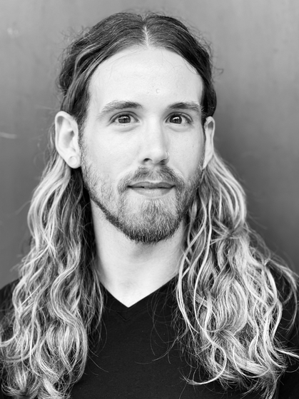 A man with long hair and beard wearing black shirt.